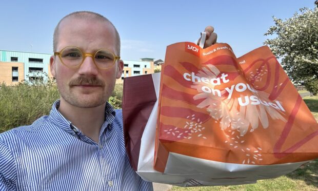 Jacob Smith holding two food bags in Dundee.
