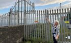 Sandra Maguire of Burntisland Harbour Access Trust beside the fence erected by Forth Ports