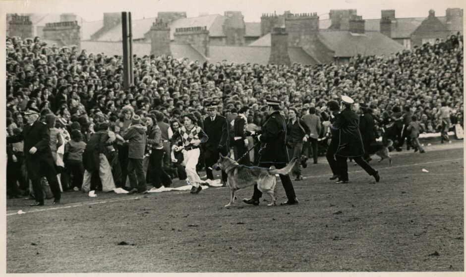 Police with dogs clear the pitch at Dens park, after a match between Rangers and Dundee in March 1975. Image: DC Thomson.
