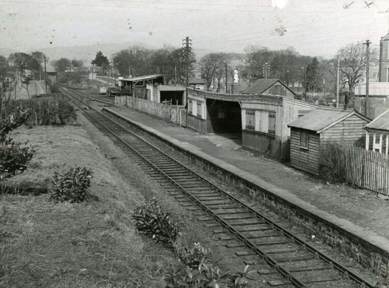 A railway station in Dundee with sheds on the right.