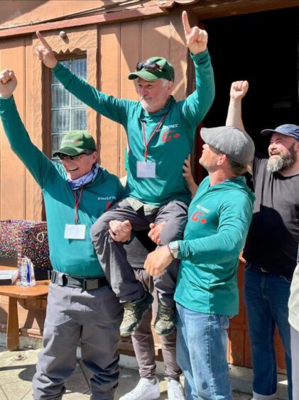 Milos Vasiljevic with arms in air being carried on shoulders of two men