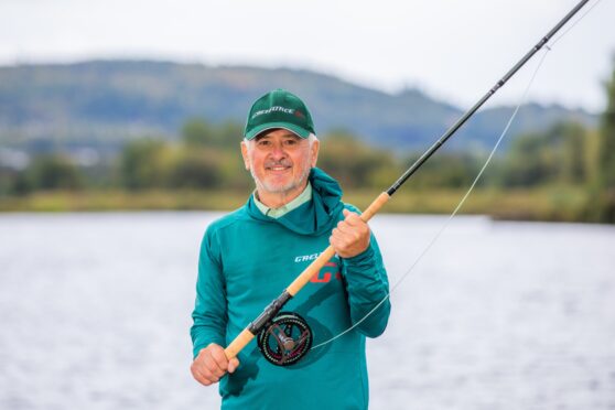 Milos Vasiljevic holding fishing rod beside river tay