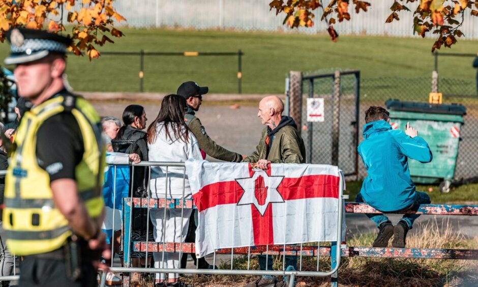 Anti-immigration protestors behind a barrier, a police officer in the foreground.