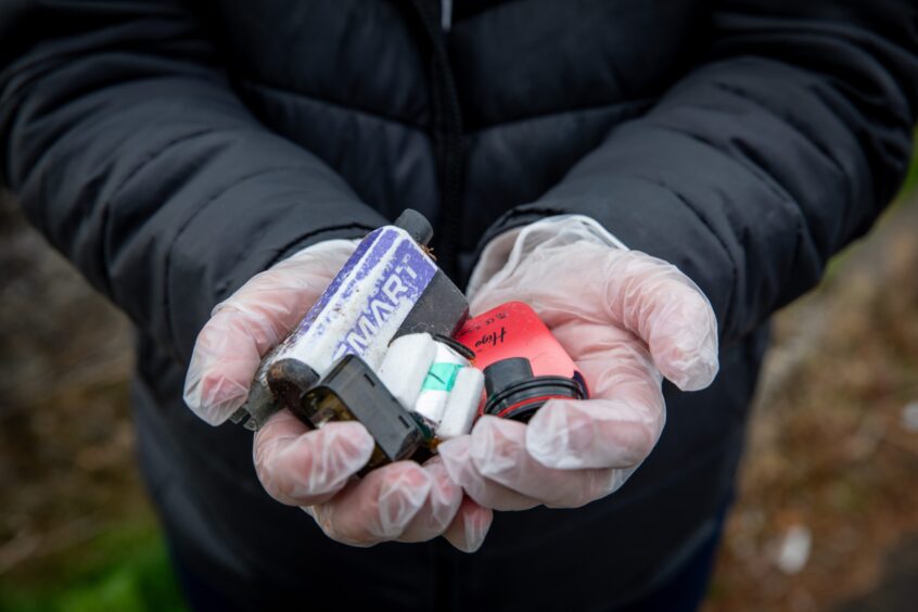 Person wearing disposable gloves holding litter from vapes in cupped hands