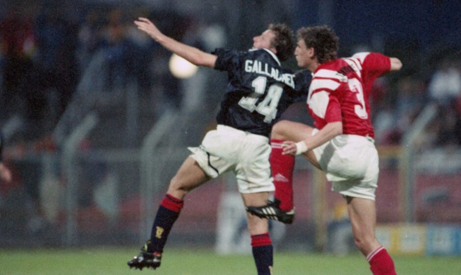 Scotland striker Kevin Gallacher rises to meet a high ball as he is challenged by a Denmark defender.