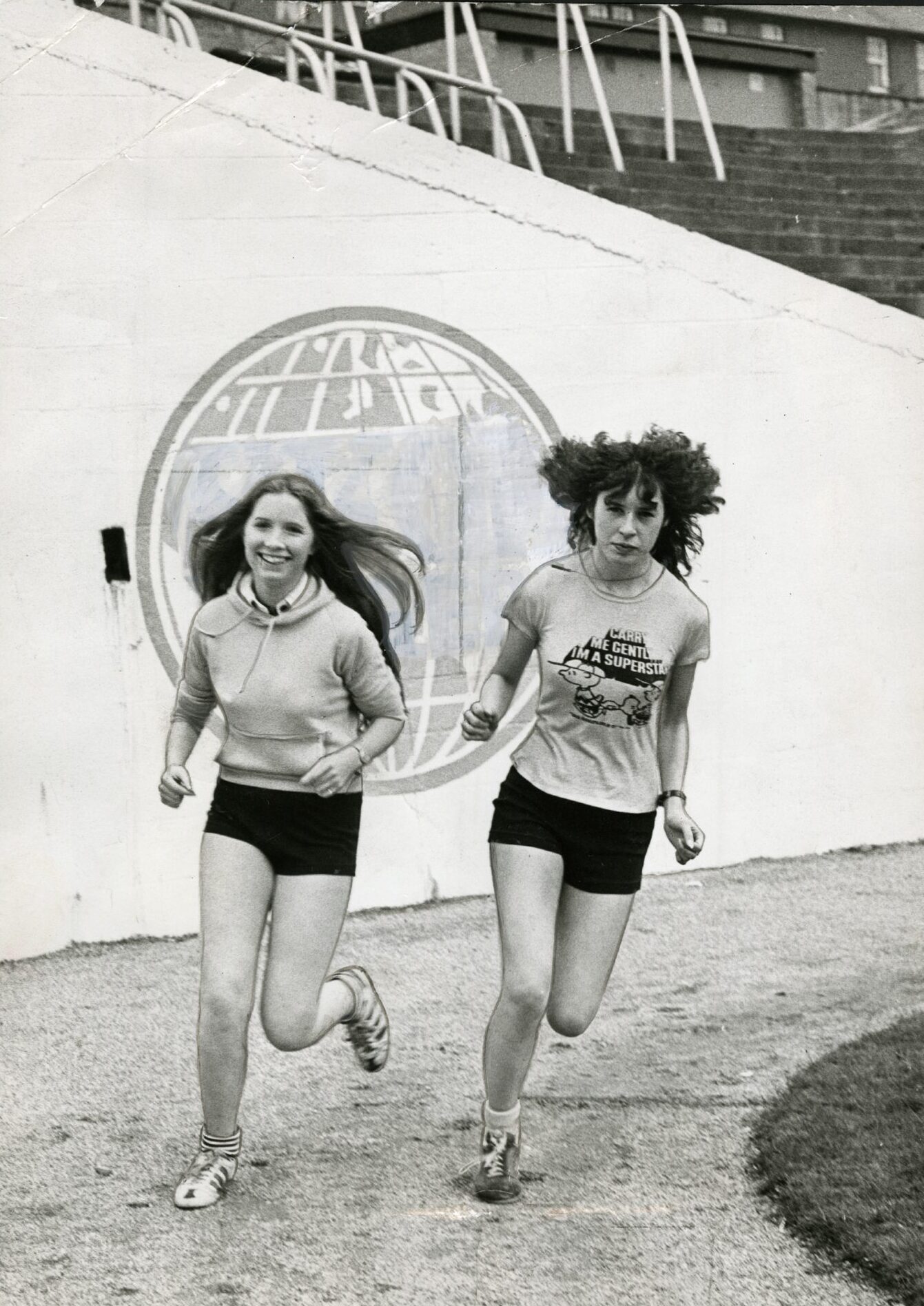 Two teenage girls run round the track at Tannadice.
