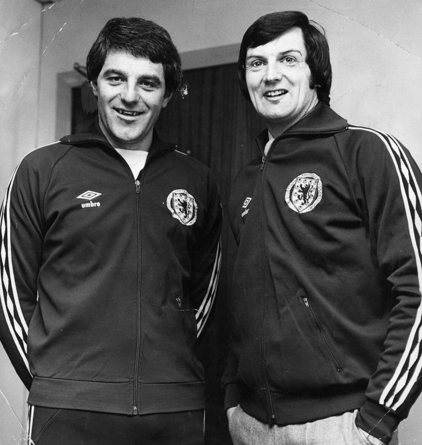 Scotland youth team coaches Walter Smith and Andy Roxburgh stand side by side. Both are wearing Scotland tracksuit tops with the Umbro diamond design on the sleeves and a large SFA badge on the chest.