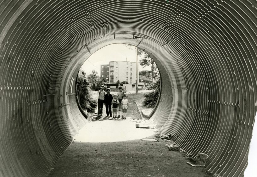 Looking through a tunnel in Whitfield Drive towards some youngsters.