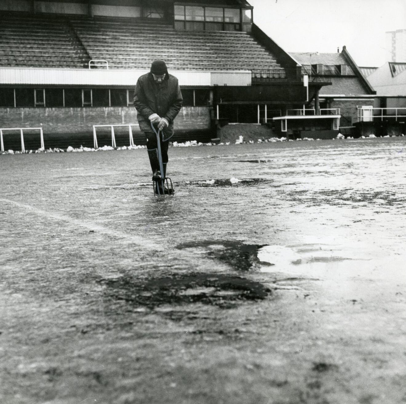 A groundsman uses a garden fork as he works on the Tannadice pitch. The grass looks frozen solid with some pools of water. Amazingly the game went ahead.