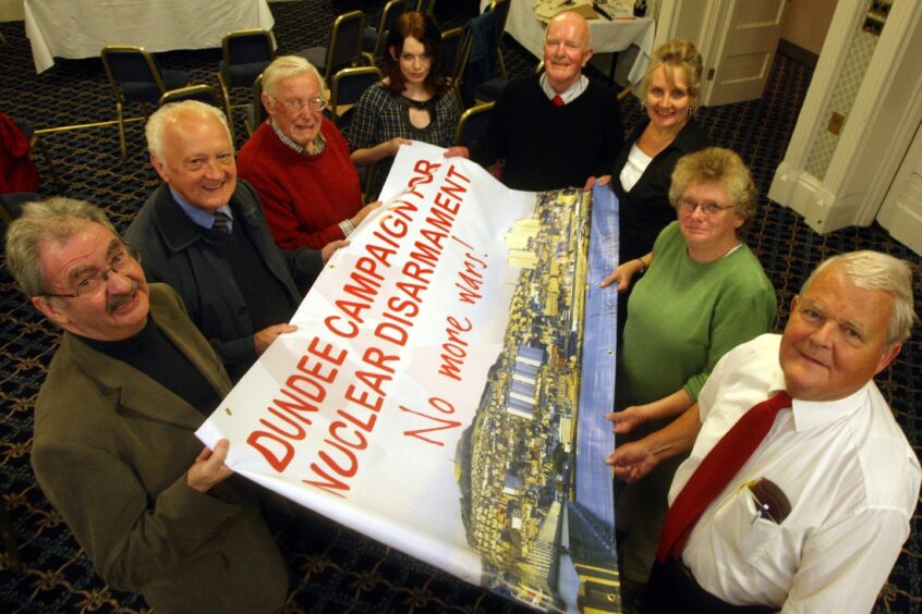 Erik Cramb with a group of CND supporters holding a large poster that shows a picture of Dundee and has the words Dundee Campaign for Nuclear Disarmament.