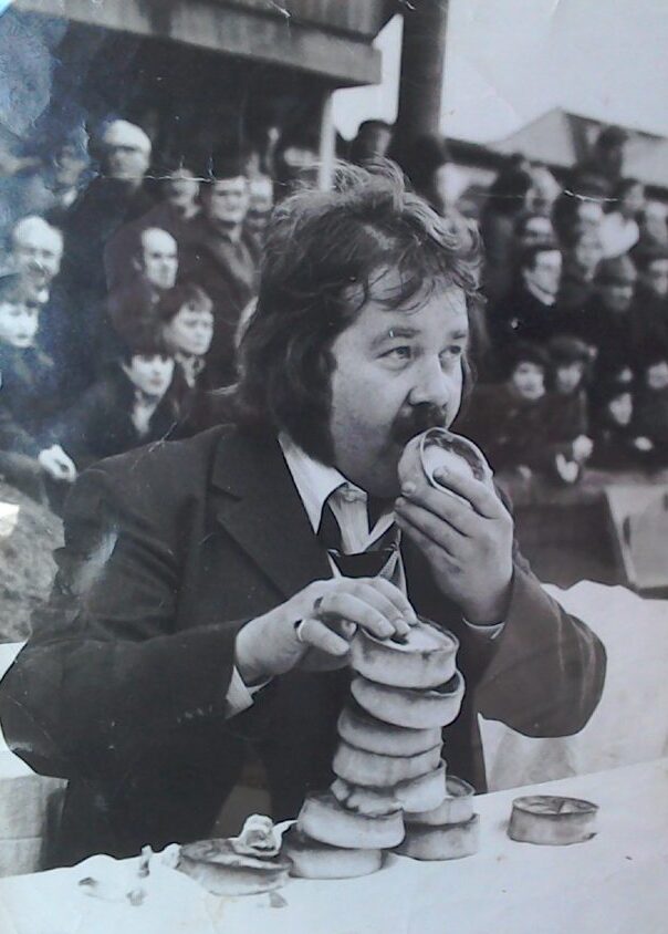 Stewart Coutts takes part in a pie-eating contest at Tannadice, which he won. He is about to devour one pie and has 11 others piled up and ready in front of him.