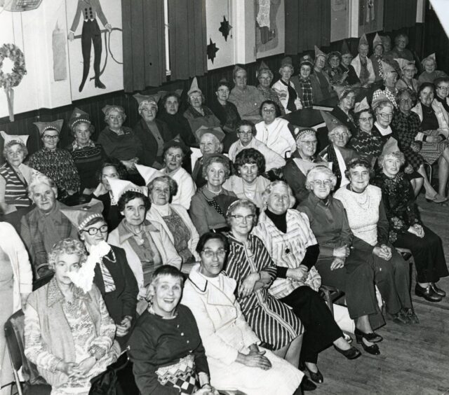 A group of old ladies in party hats seated for a show in Dundee.