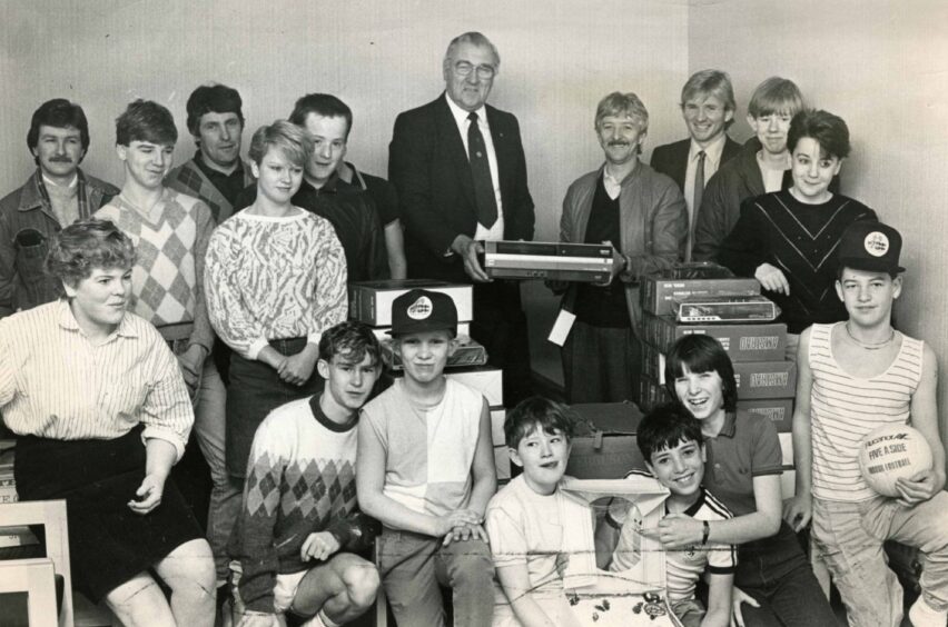 A man hands over electronic items to a group of Dundee youngsters in the 1980s.