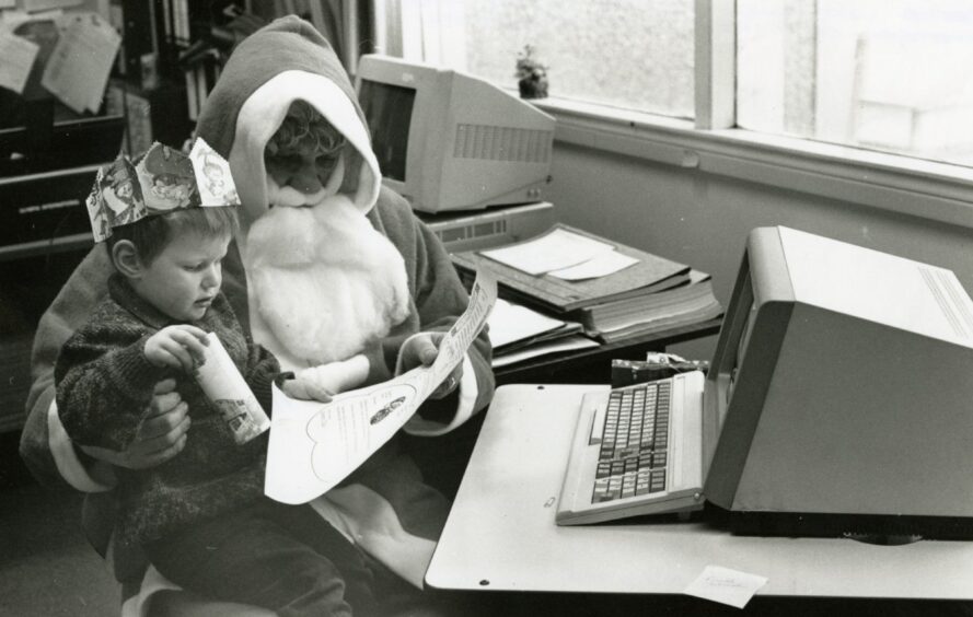 Santa and a small child beside a computer in Dundee.
