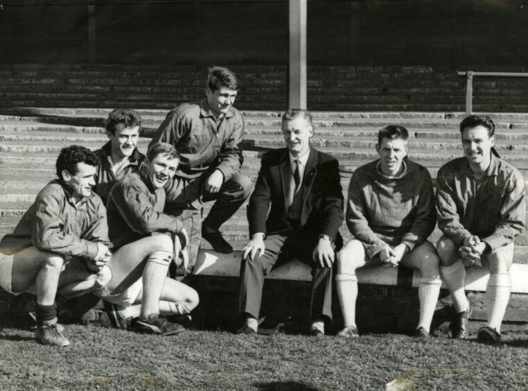 Bobby Ancell sits with some of the Dundee F players beside the pitch