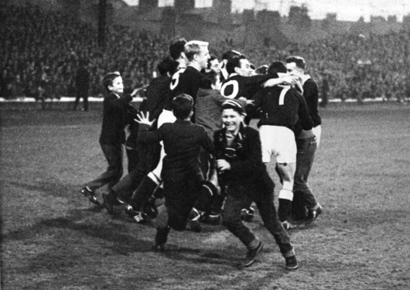 a group of Dundee players celebrate on the pitch after a 2–0 win over St Mirren in April 1962. Young fans run towards them