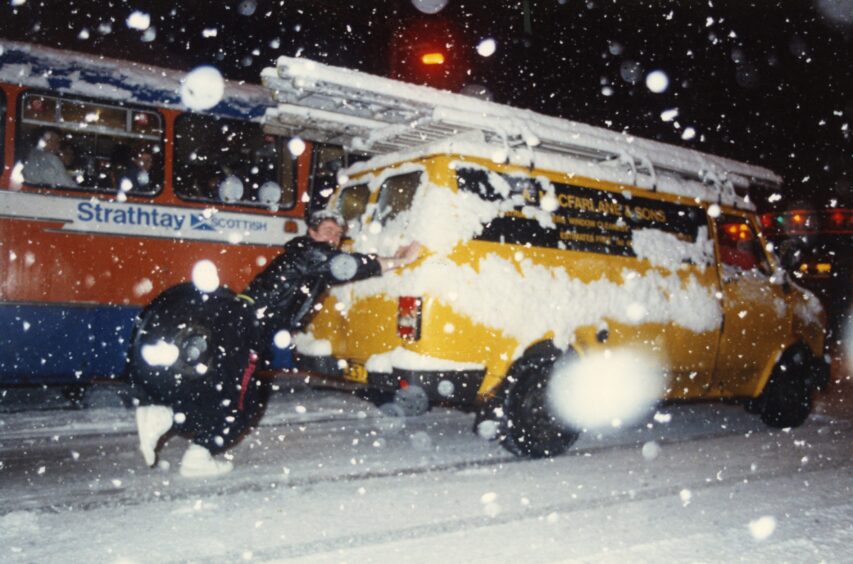 Someone pushing a van in the snow in Dundee. 