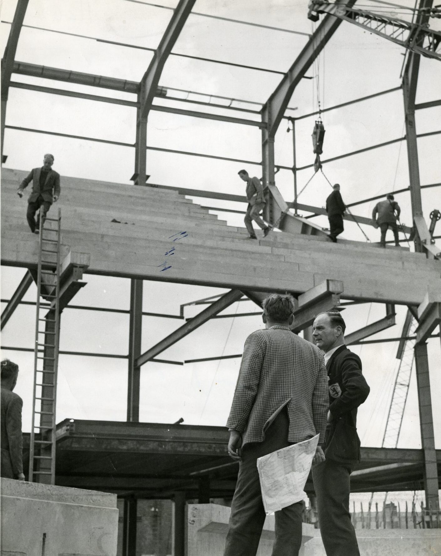 Jerry Kerr looking at a stand, with workers on the scaffolding