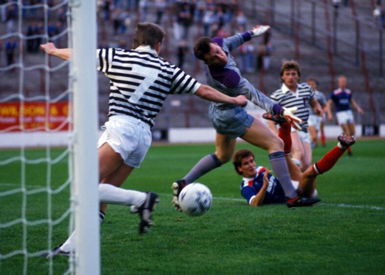 McKinlay, pictured lying on the ground, scores past Queen's Park goalkeeper Stephen Ross in 1987.