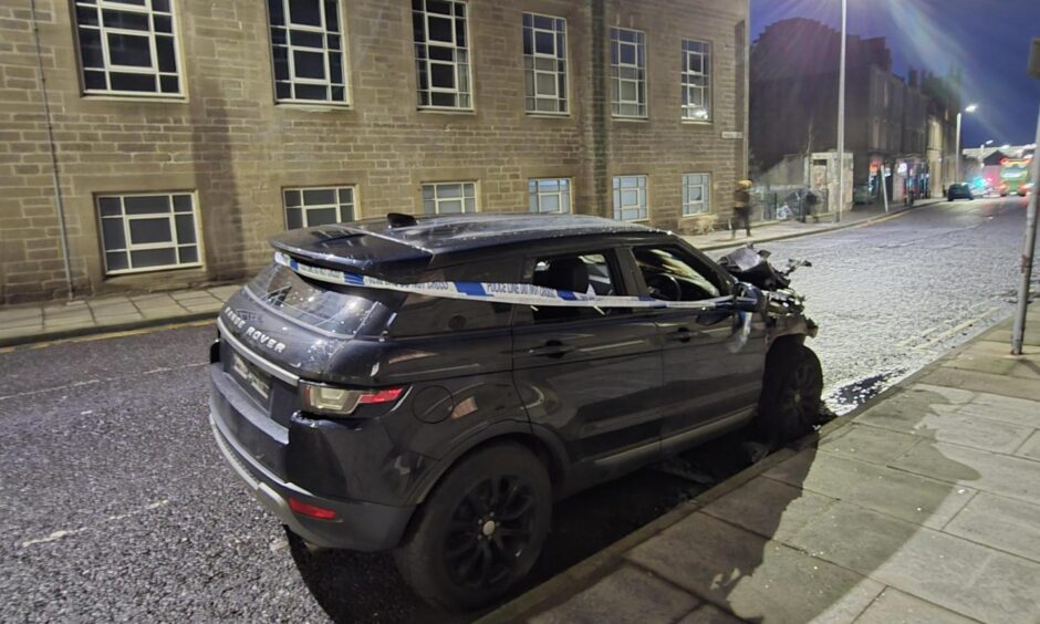 Police tape has been stretched along the side of the car.