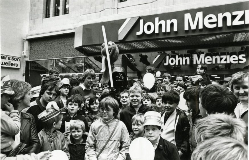 Darth Vader, with lightsaber, surrounded by people outside the new Dundee store