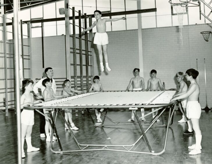 A boy bouncing on a trampoline in the school gym