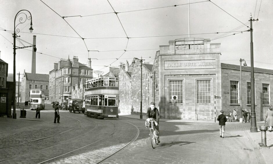 A boy on a bike rides down the road in front of a tram.