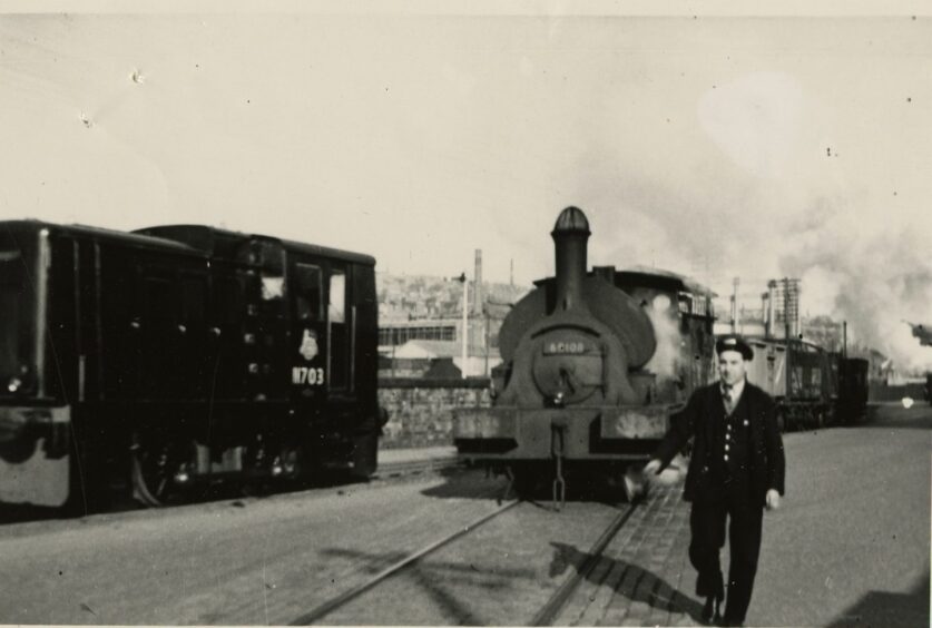 A man stands beside two trains on the tracks.