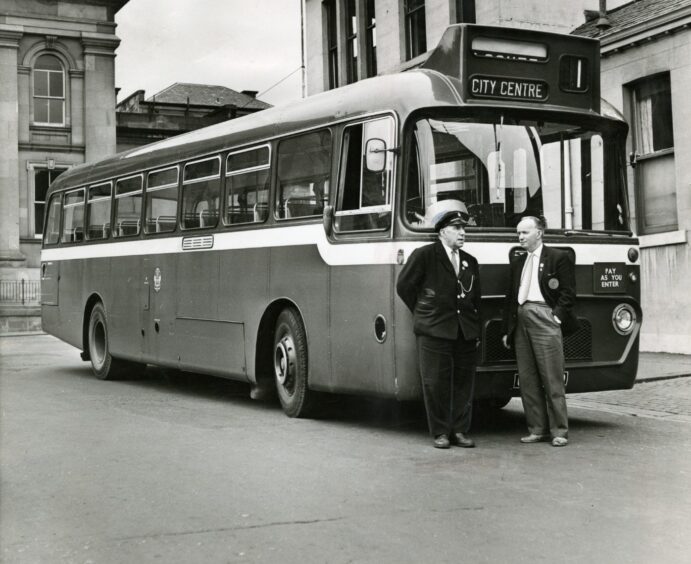 two men stand beside a single-decker