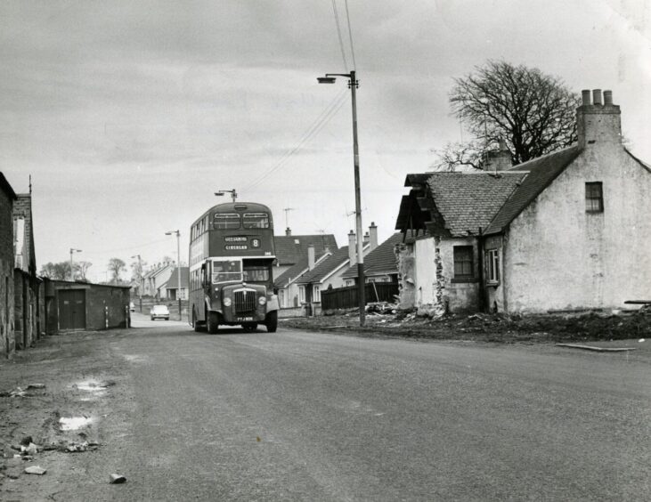A Dundee “circular” bus heading through Balgillo Road, past a partially demolished home, in April 1965