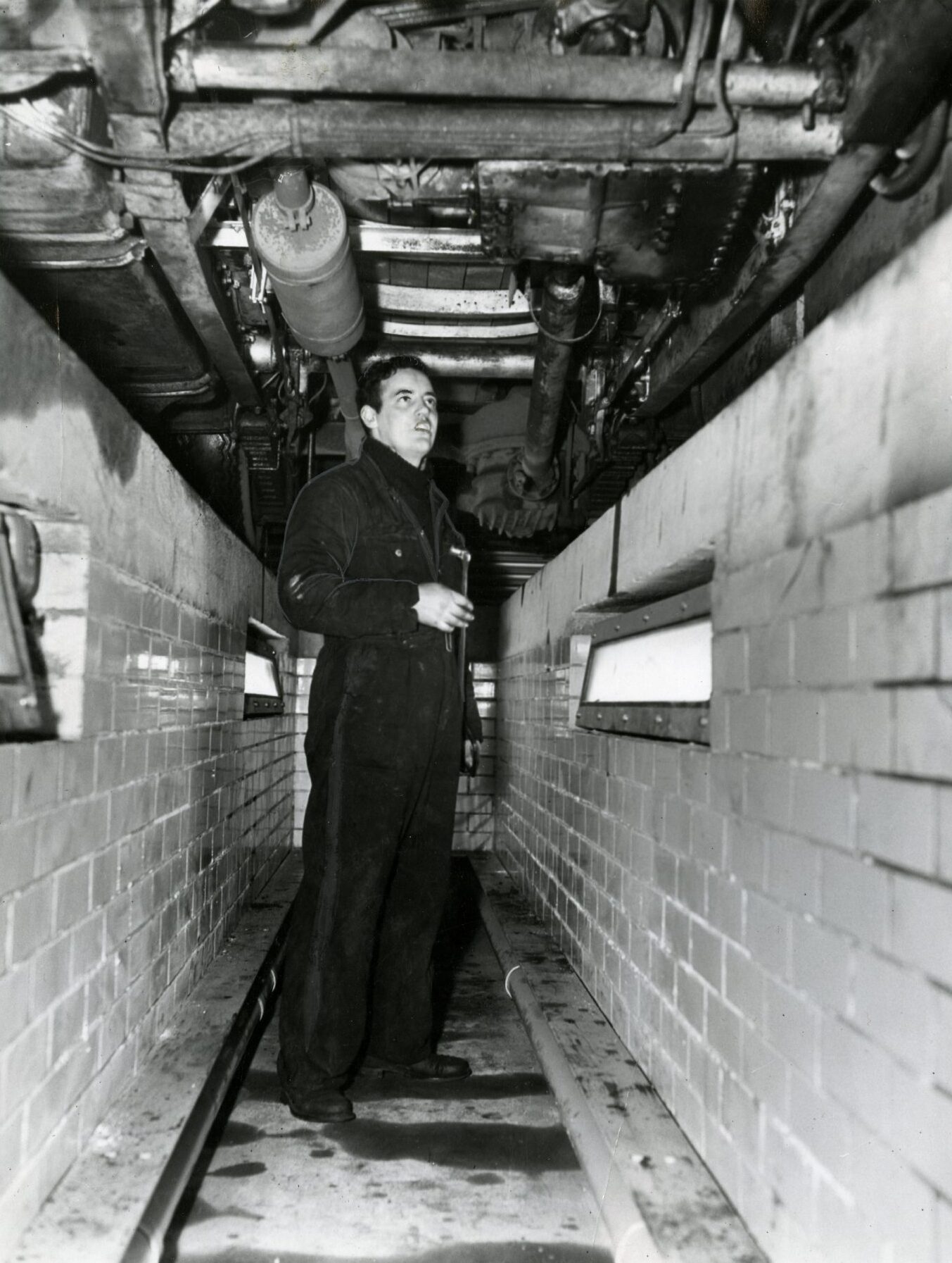 a mechanic working beneath a bus in the inspection pit.