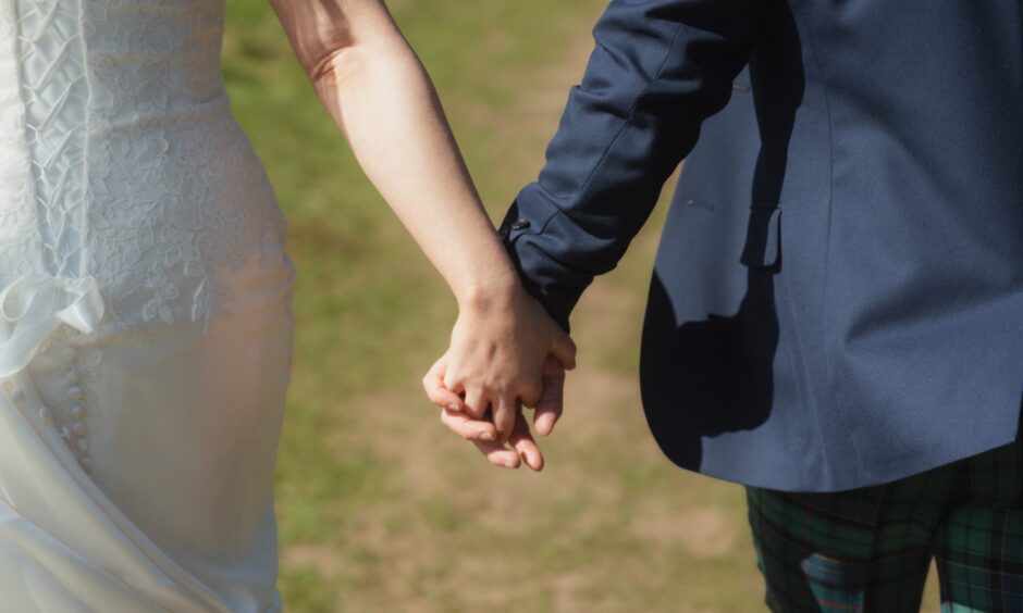 Close up of couple holding hands on their wedding day.