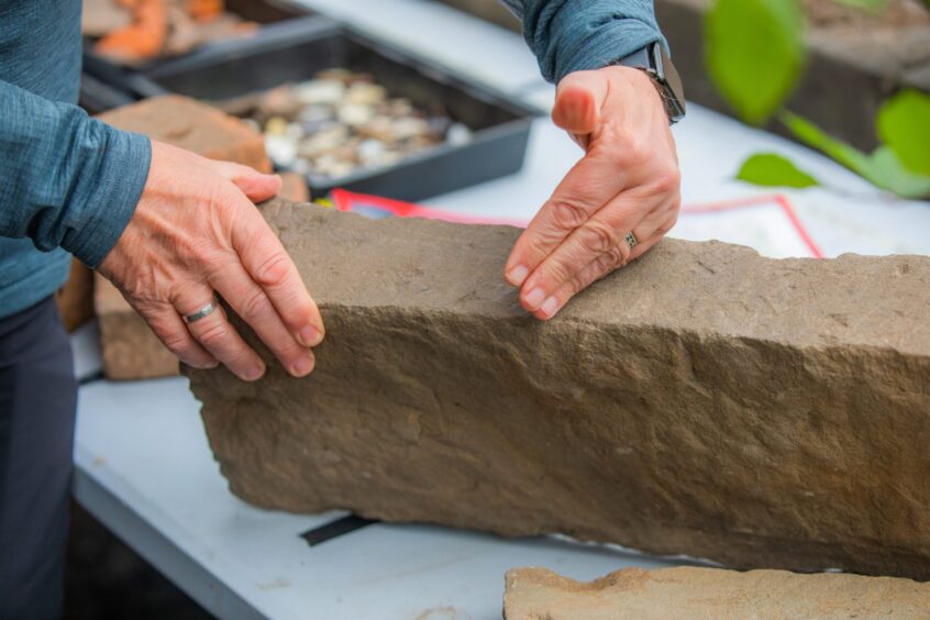 Person holding large piece of stone on trestle table
