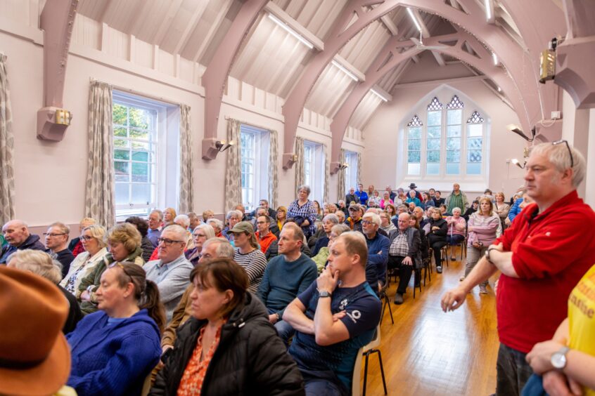Large gathering of people at public meeting in Errol village hall