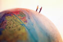 two people standing on a world globe