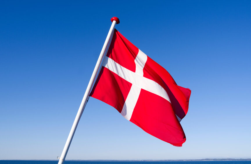 Danish flag flying against blue sky.