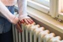 A woman placing her hands on a radiator.