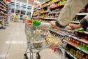 A shopper pushes their trolley down a supermarket aisle.