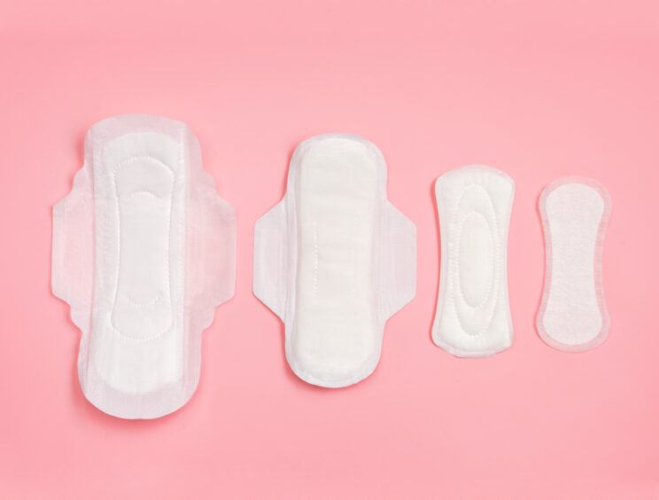 A selection of menstrual pads displayed against a pink background.