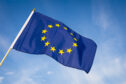 EU flag flying against a sunny sky.