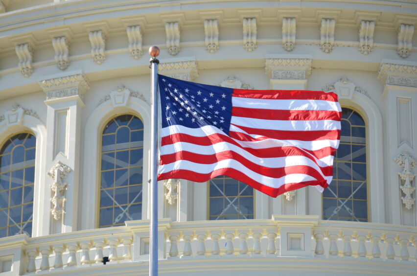 US flag flies infront of the Capitol building.