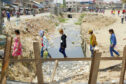 Apparel workers cross a makeshift bridge over a flooded area. Image credited to the International Labour Organization's Better Work partnership.