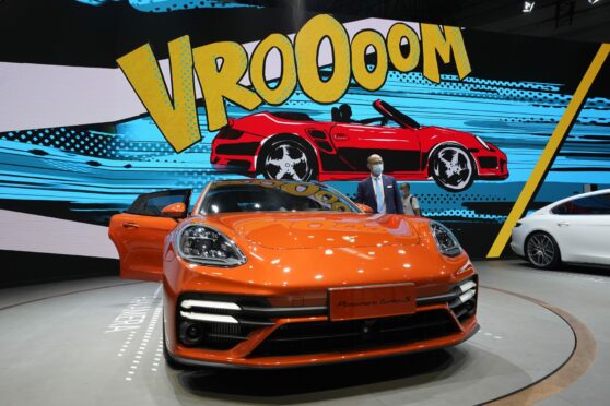 Visitor poses by a Porsche Panamera Turbo S sports car at the Auto China 2020 show in Beijing