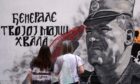 Two women in front of a mural of former Bosnian Serb military chief and convicted war criminal Ratko Mladic that has been vandalised with paint in Belgrade
