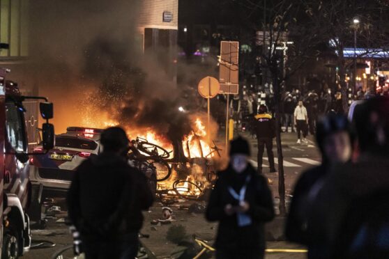 Cars are set alight as protests against Covid lockdown restrictions turn violent in Rotterdam, Netherlands on Friday. At least seven people are injured as police struggle to get rioting under control
