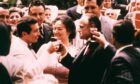 Don Vito Corleone (played by Marlon Brando), right, clinks glasses with wedding guest Johnny Fontane (Al Martino) as wife Carmela (Morgana King) stands by and smiles in The Godfather