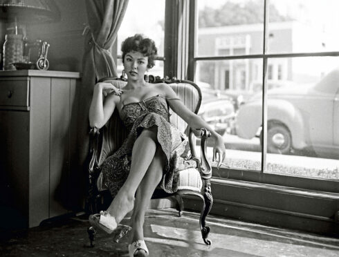 Actress Rita Moreno, sitting on a couch, February 1954.