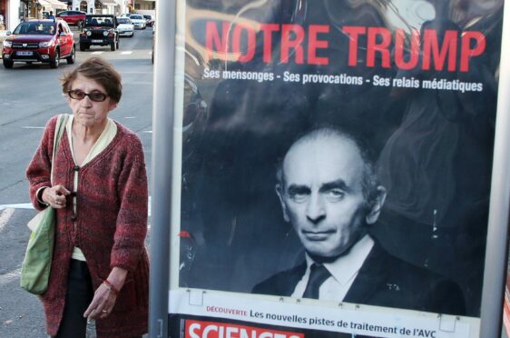 A woman walks past a poster of Eric Zemmour that reads ‘Our Trump’ in French in Biarritz, France
