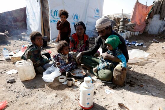 A family have a meal at a camp in Yemen