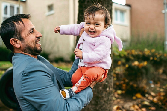Omid Asak plays with daughter Maryiam, one, as                      his family settle into their new life in North Ayrshire.
